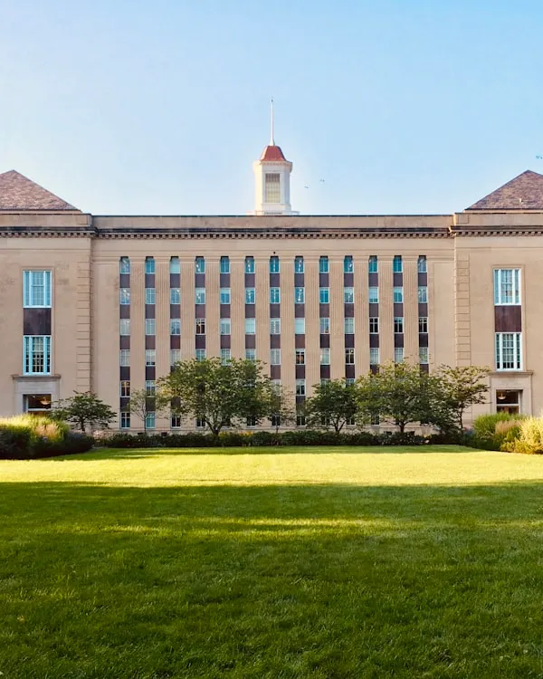 A classic red brick university building under a blue sky, representing public institutions.